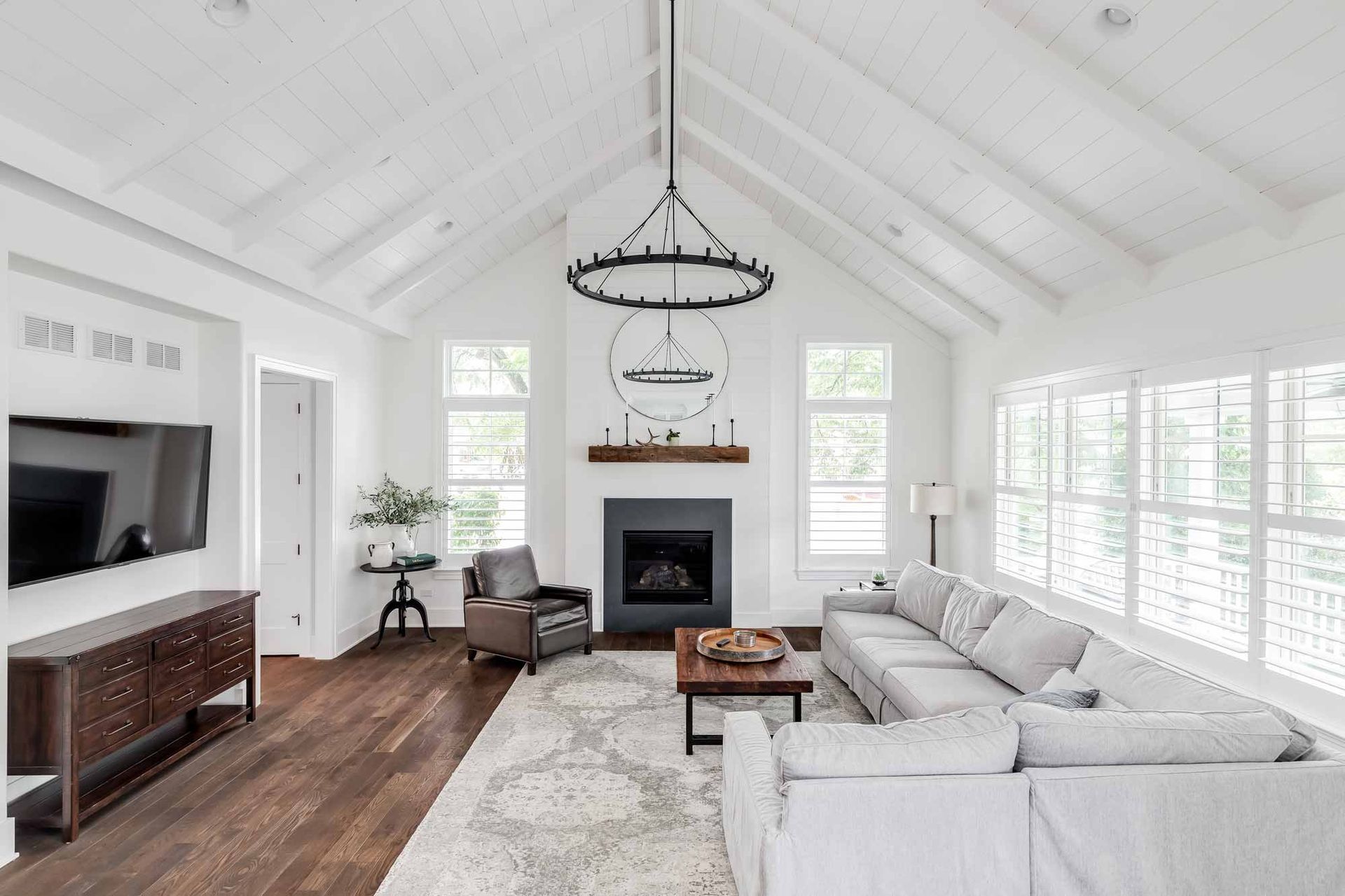 Bright living room with white vaulted ceiling, fireplace, sectional sofa, and wood floors