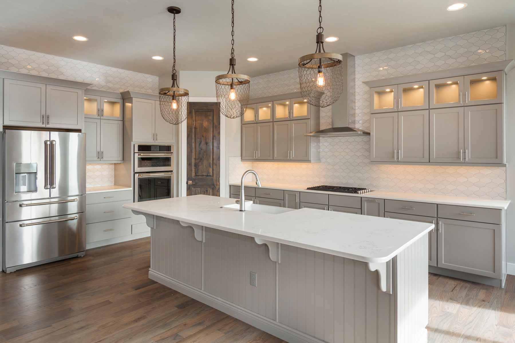 Bright modern kitchen with white cabinets, stainless appliances, and a large island under pendant lights