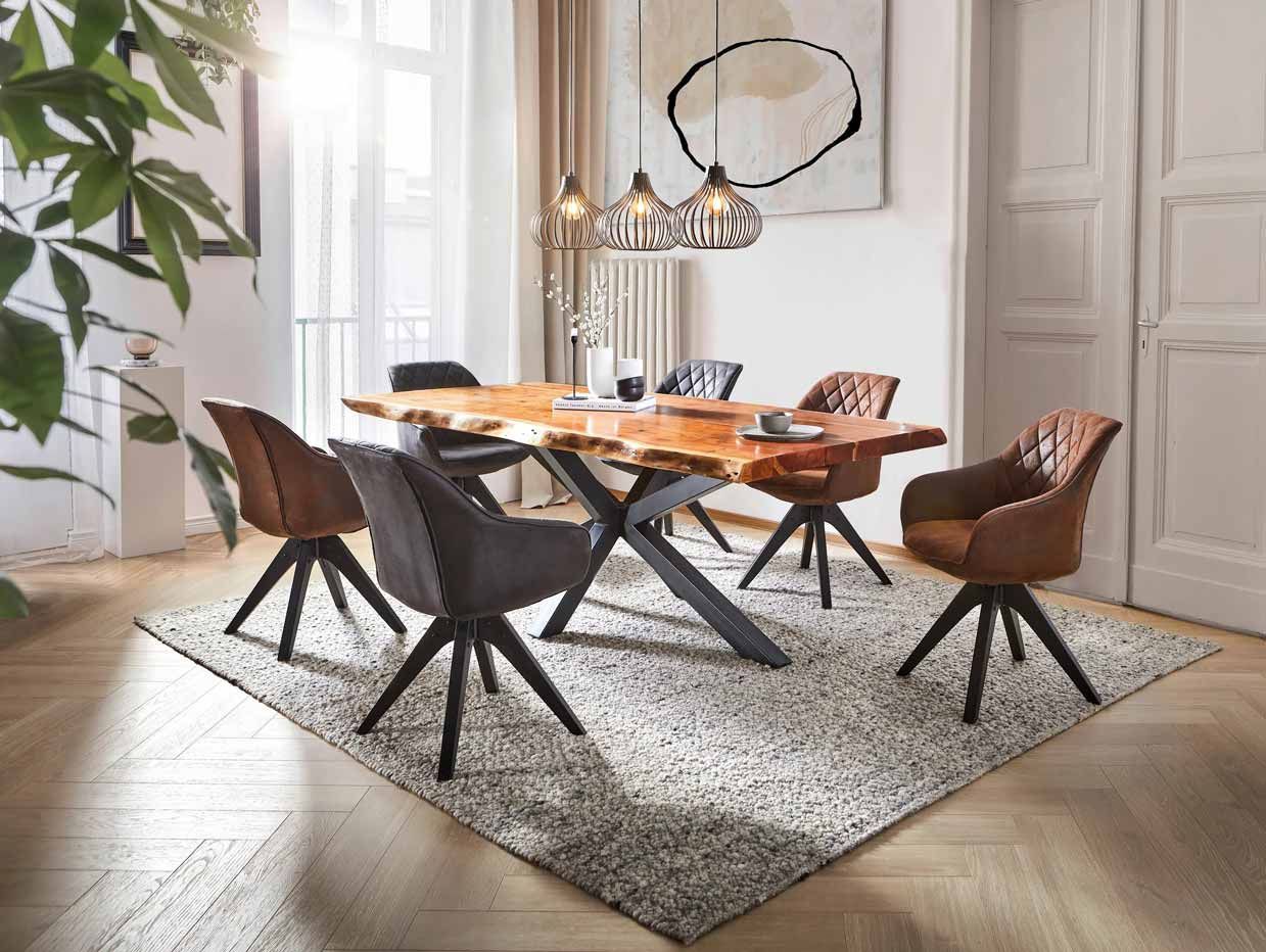 Modern dining room with a wooden table, brown chairs, and a chandelier on a light rug near tall windows.