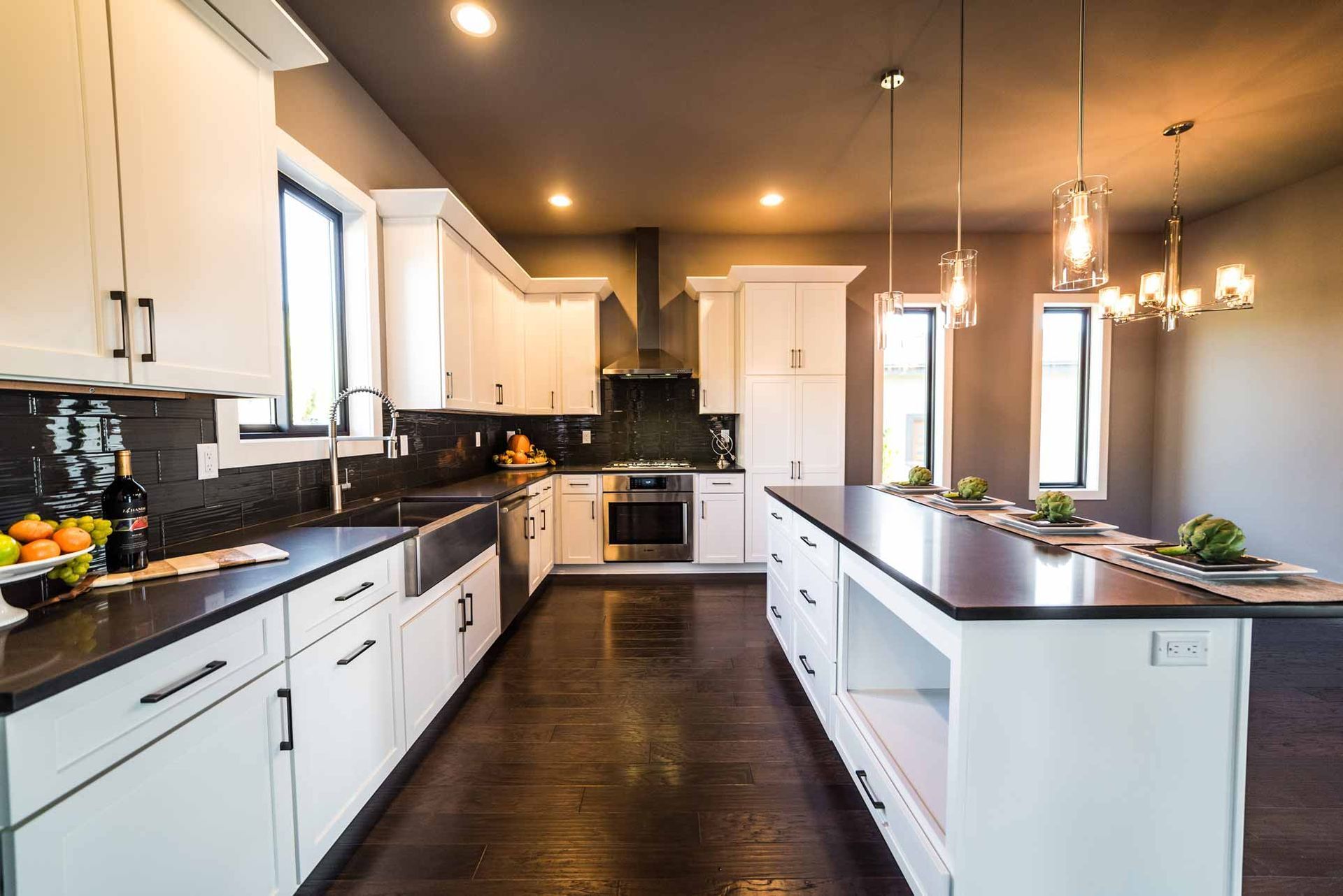 Modern kitchen with white cabinets, dark countertops, and a large island with pendant lights