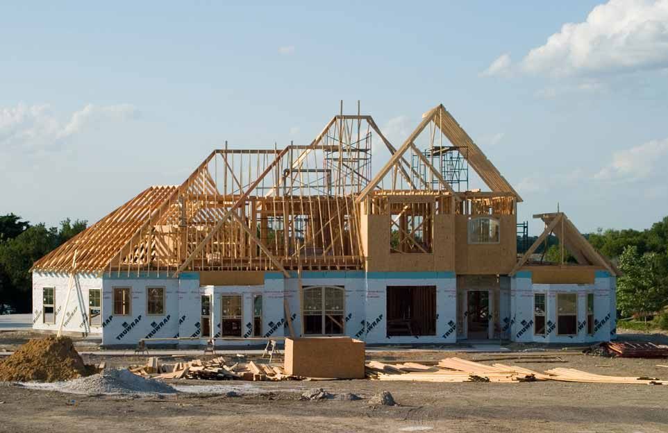 Partially built house with wooden framing and white exterior walls at a construction site