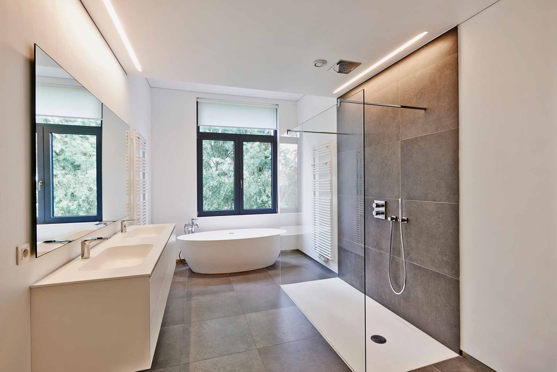 Modern bathroom with double vanity, window seat, and glass walk-in shower