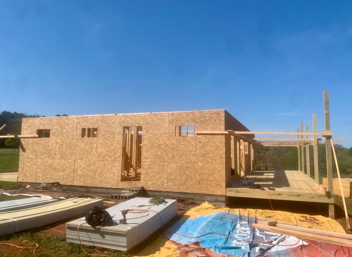 Partially built brick house with wooden framing and construction materials under a blue sky