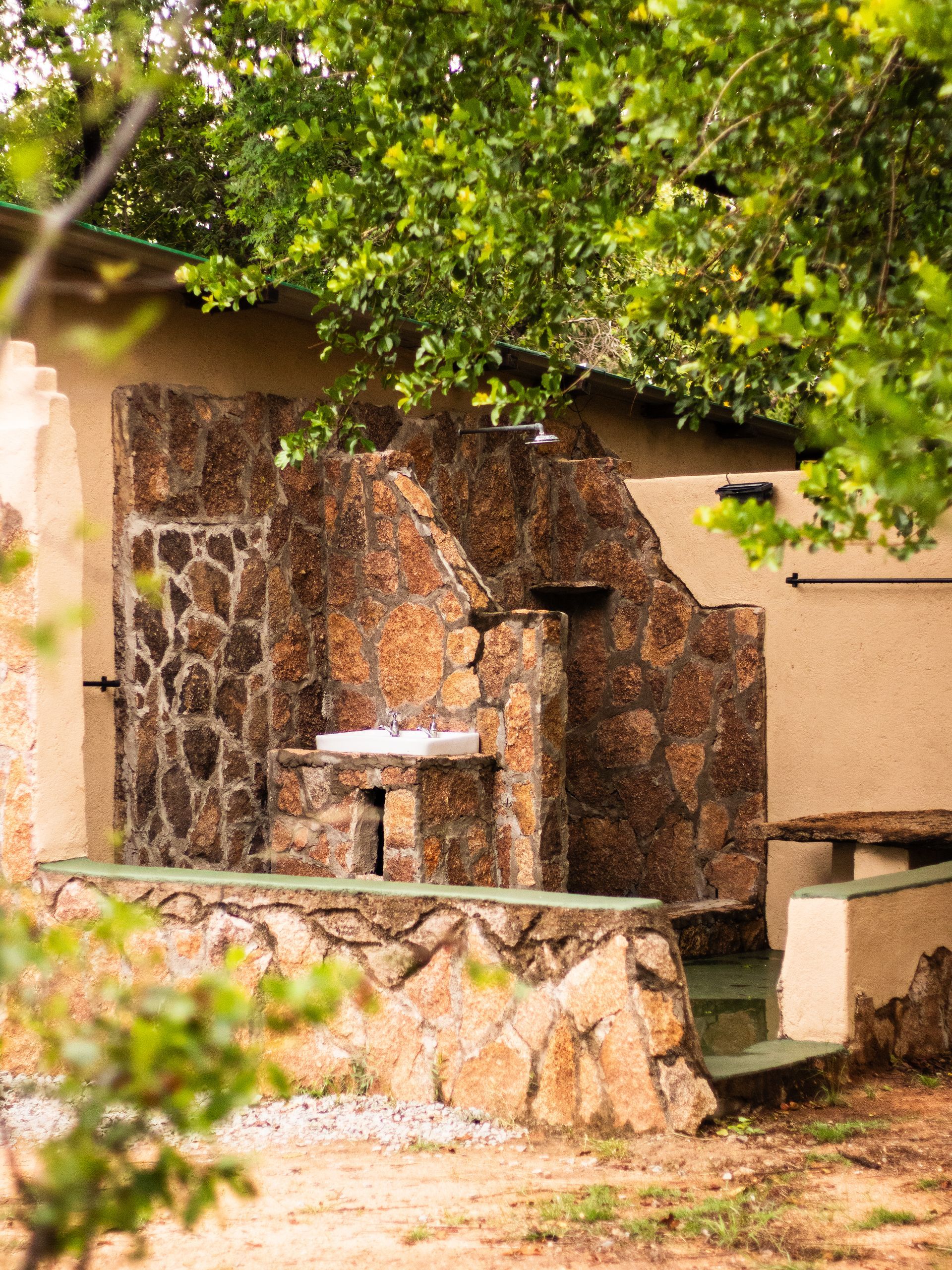 Outdoor stone Shower area with steps and overhanging trees.
