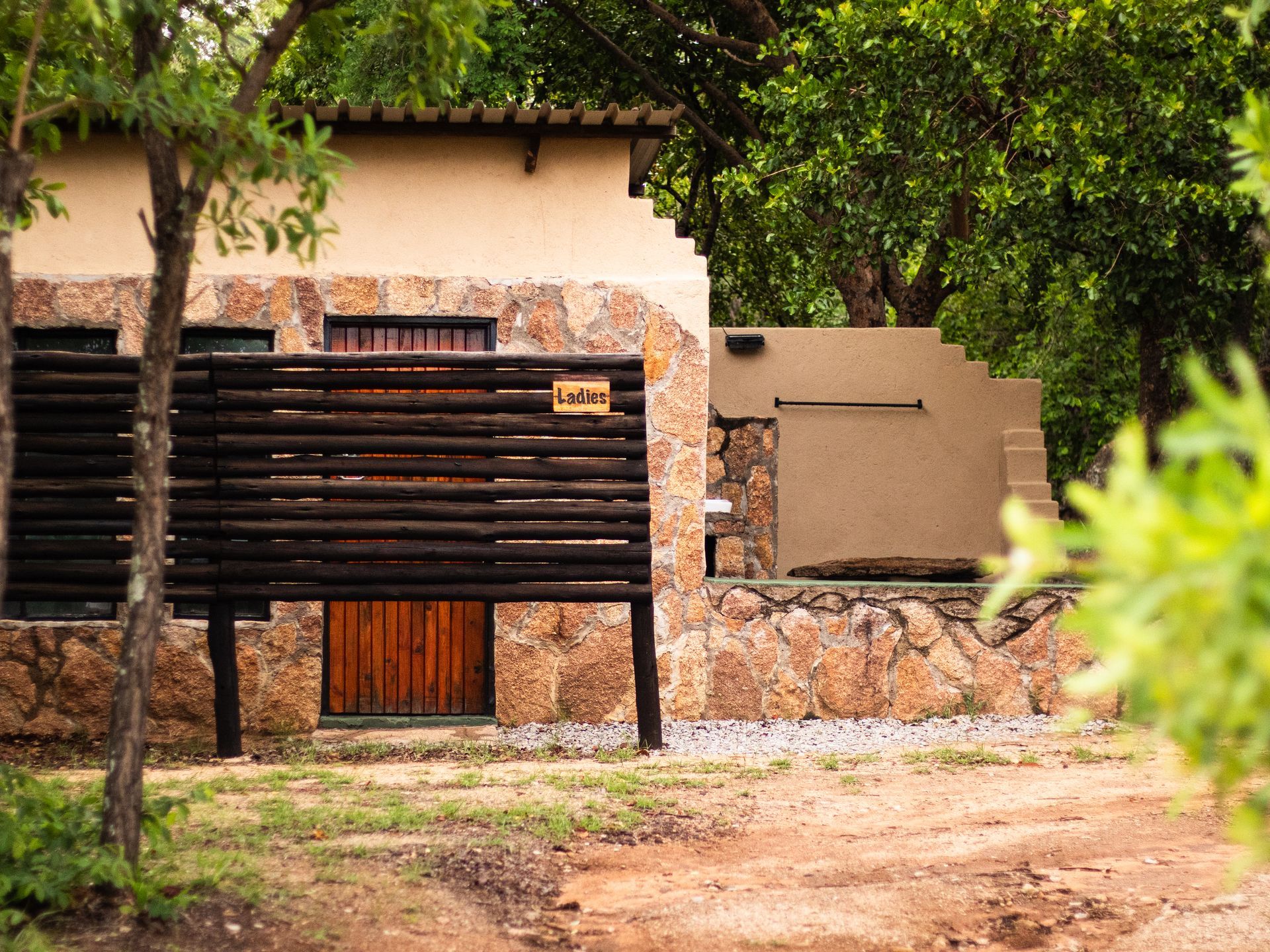 Stone and wood building in a natural setting; a wooden screen covers part of the structure.