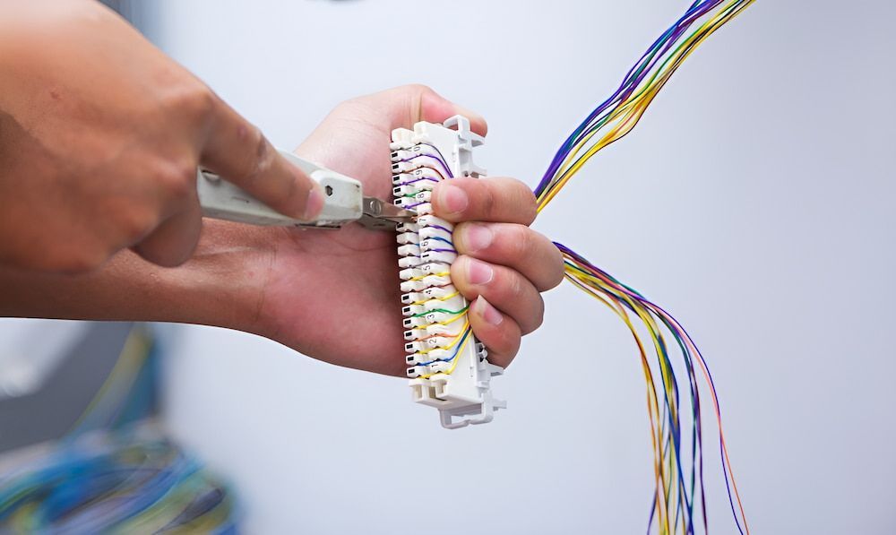 A Person Is Holding A Bunch Of Wires In Their Hands — In-Line Electrical Southern Highlands in Carrick, NSW