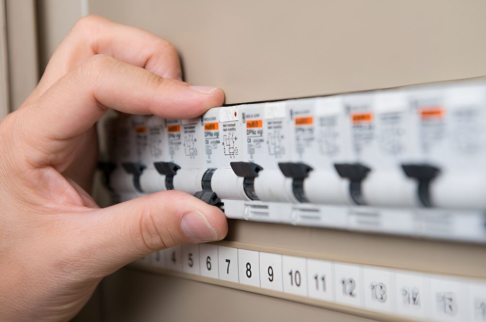 A Person Is Holding A Circuit Breaker In Their Hand — In-Line Electrical Southern Highlands in Bowral, NSW