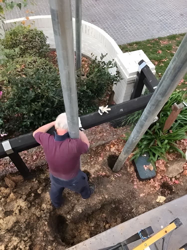 A Man Is Kneeling Down In The Dirt Next To A Metal Pole β In-Line Electrical Southern Highlands in Carrick, NSW