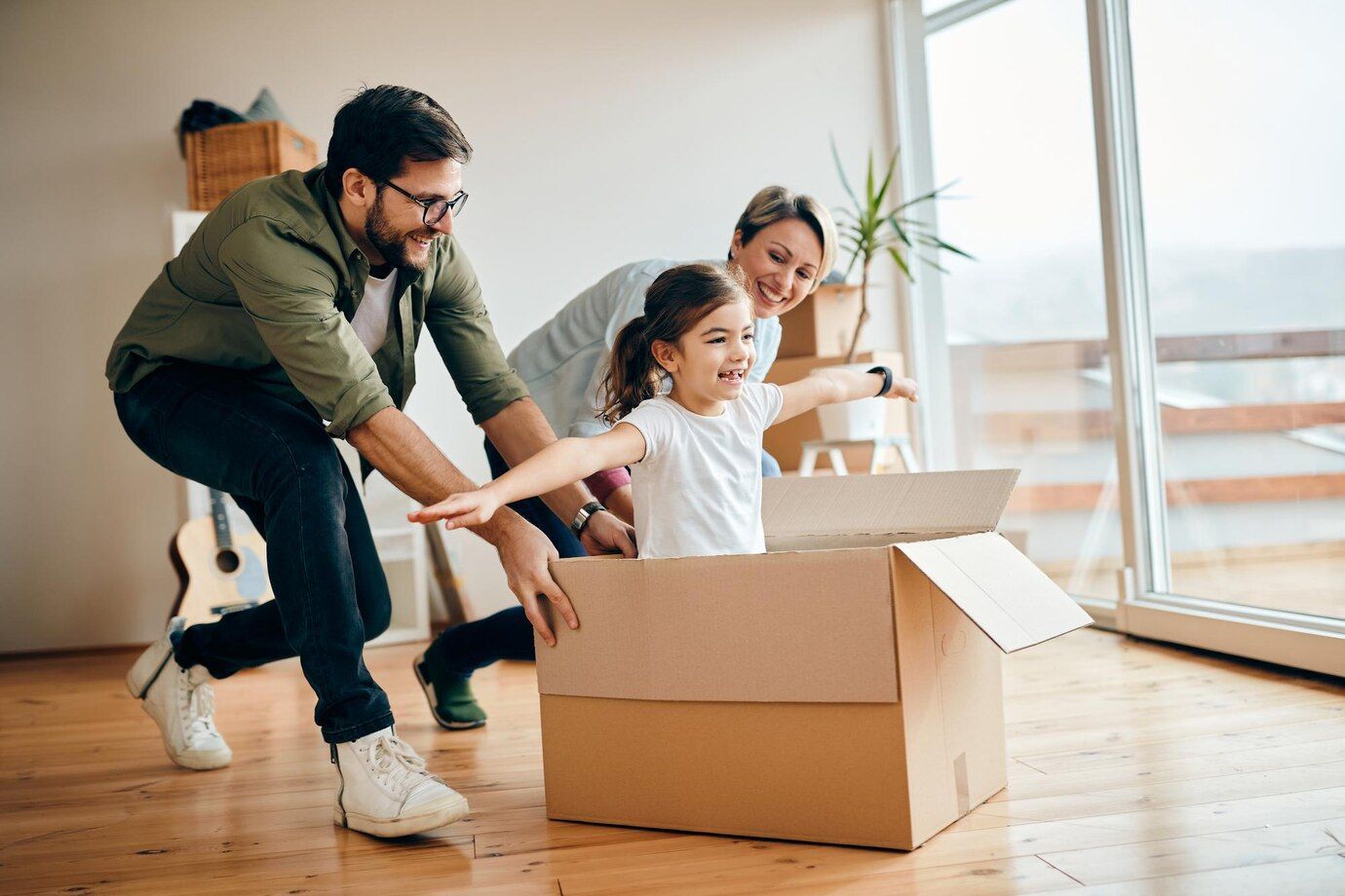 Una familia juega en una caja de cartón en su nuevo hogar.