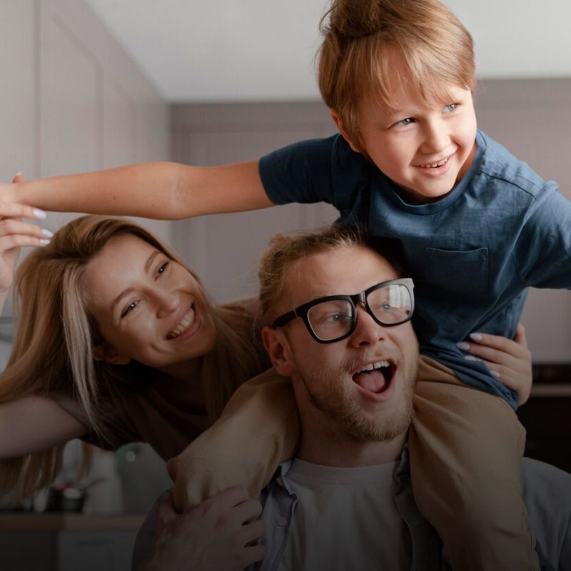 Un hombre con gafas lleva a un niño sobre sus hombros.