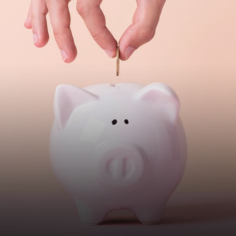 Una persona está poniendo una moneda en una alcancía.
