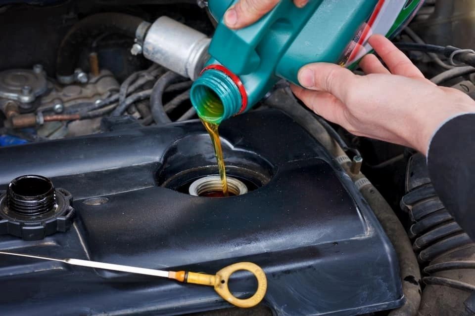 Person pouring oil into a car engine. | Frontline Auto Repair