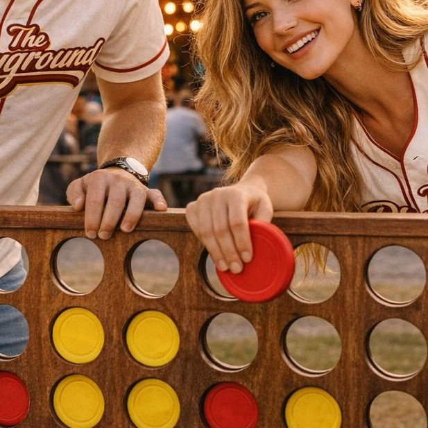 Two people playing Connect Four at a stadium, with red and yellow discs on the board.