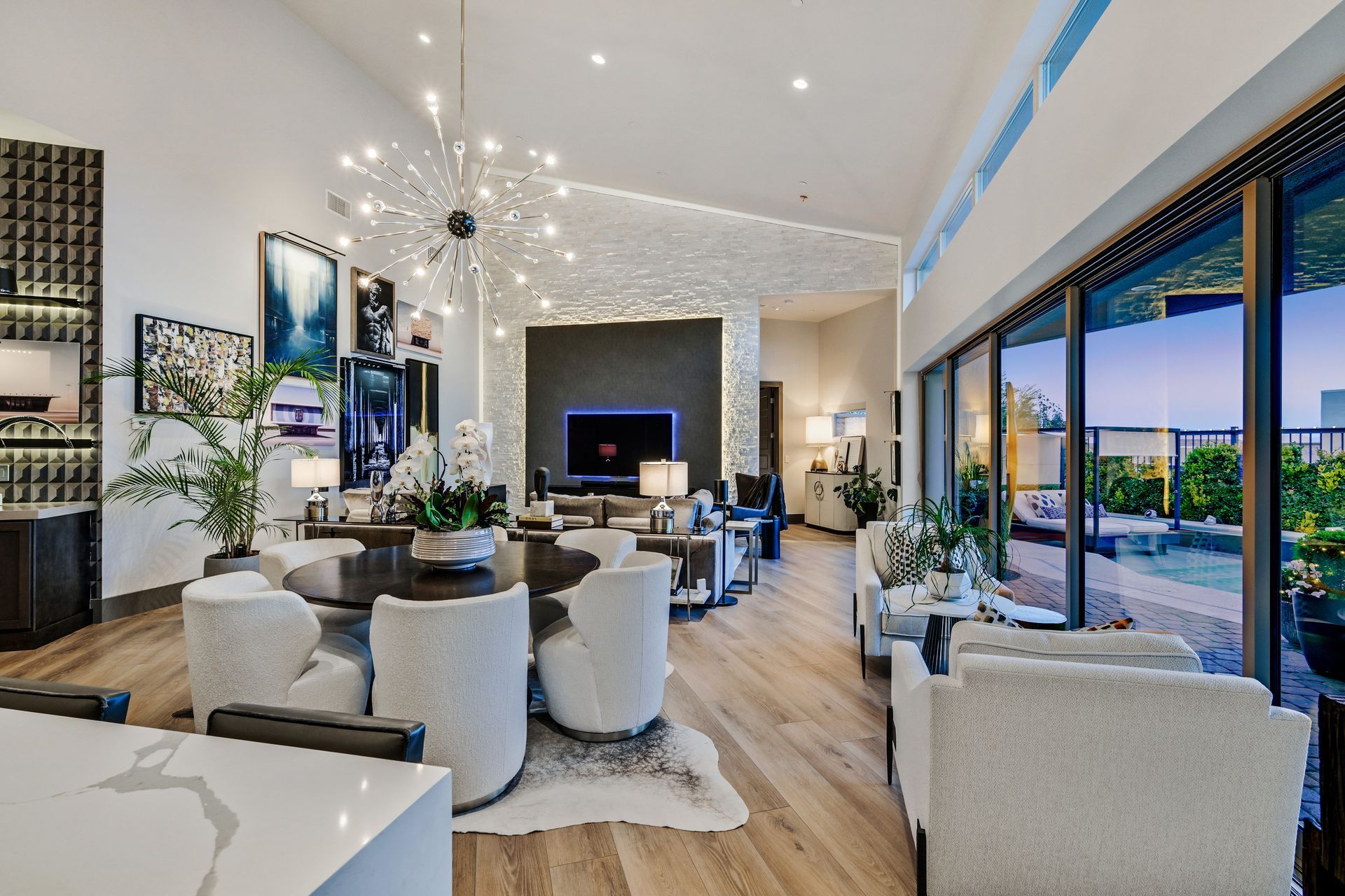 Spacious modern living room with open layout, light wood floors, and large windows overlooking a patio.