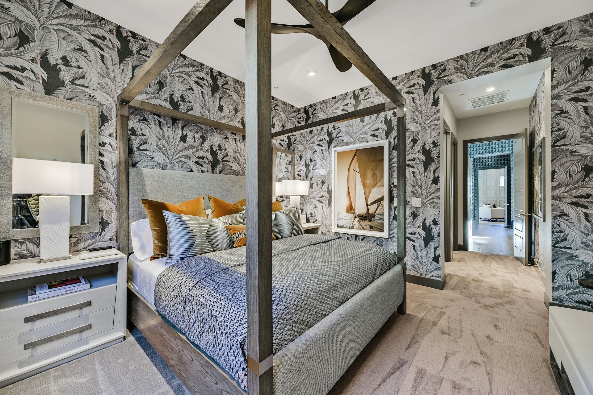 Bedroom with a canopy bed, patterned wallpaper, nightstand with lamp, and a hallway view.