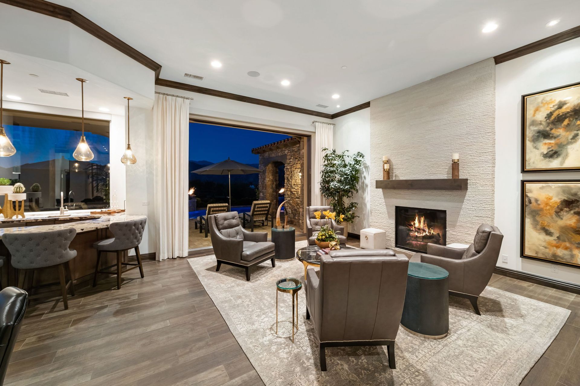 Living room with fireplace, chairs, and open doors to an outdoor patio at dusk.