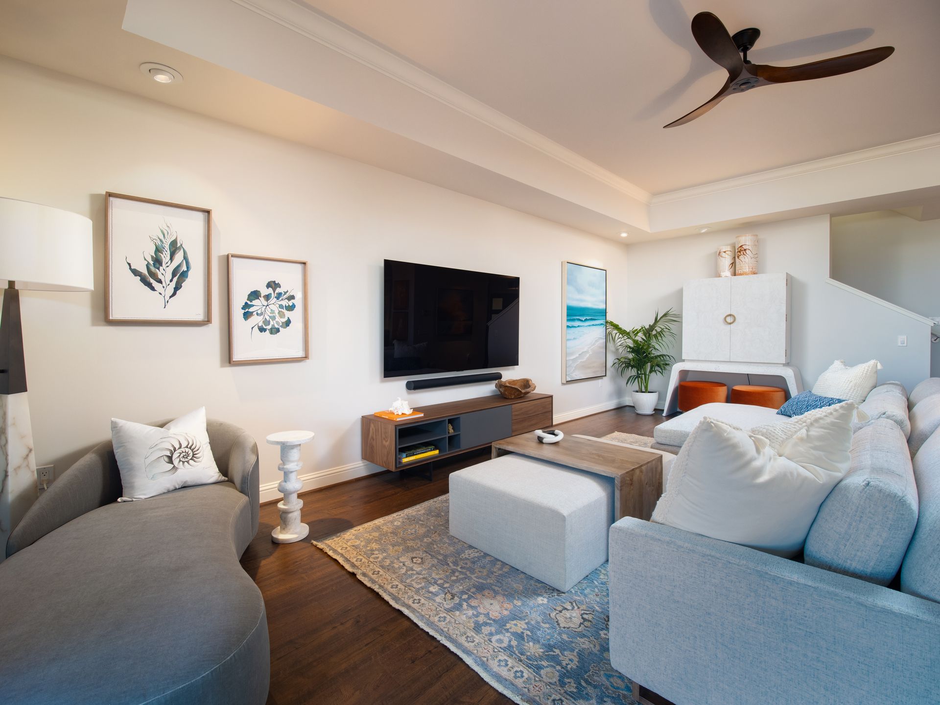 A living room with a couch , chair , television and ceiling fan.