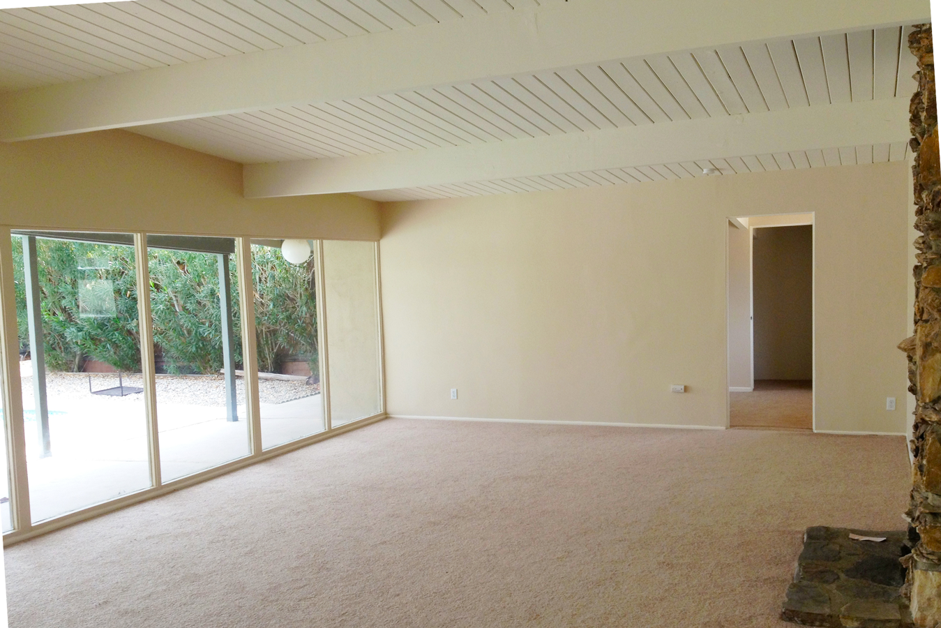 An empty living room with a fireplace and lots of windows