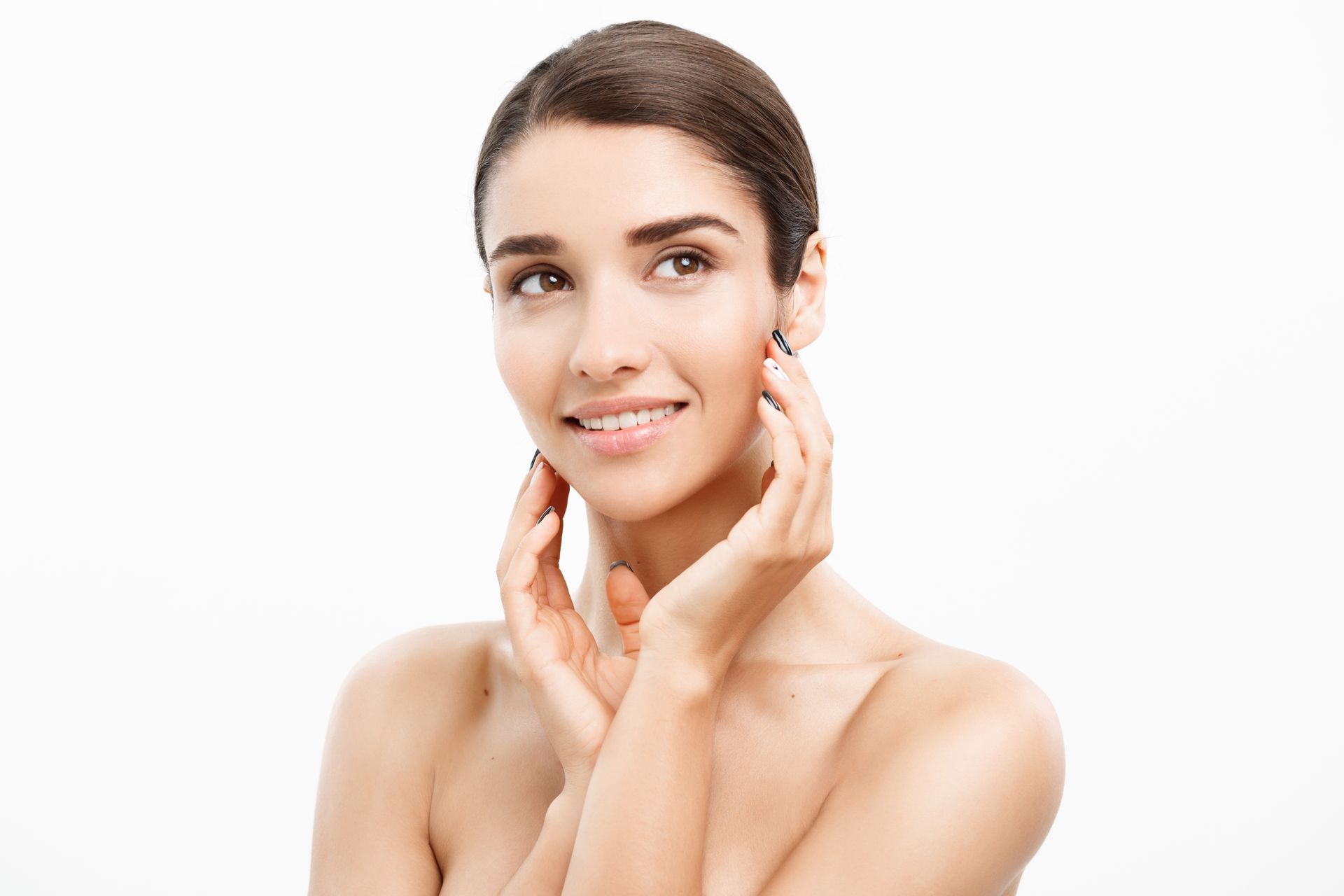 A woman is touching her face with her hands and smiling.