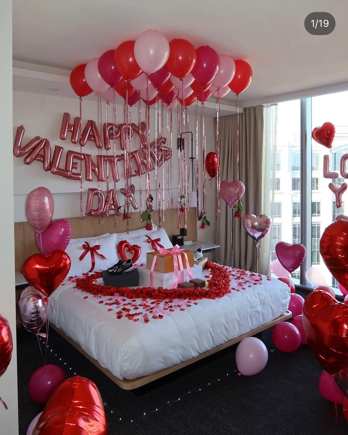 A Valentine's Day bedroom decorated with red and pink balloons, roses, and 