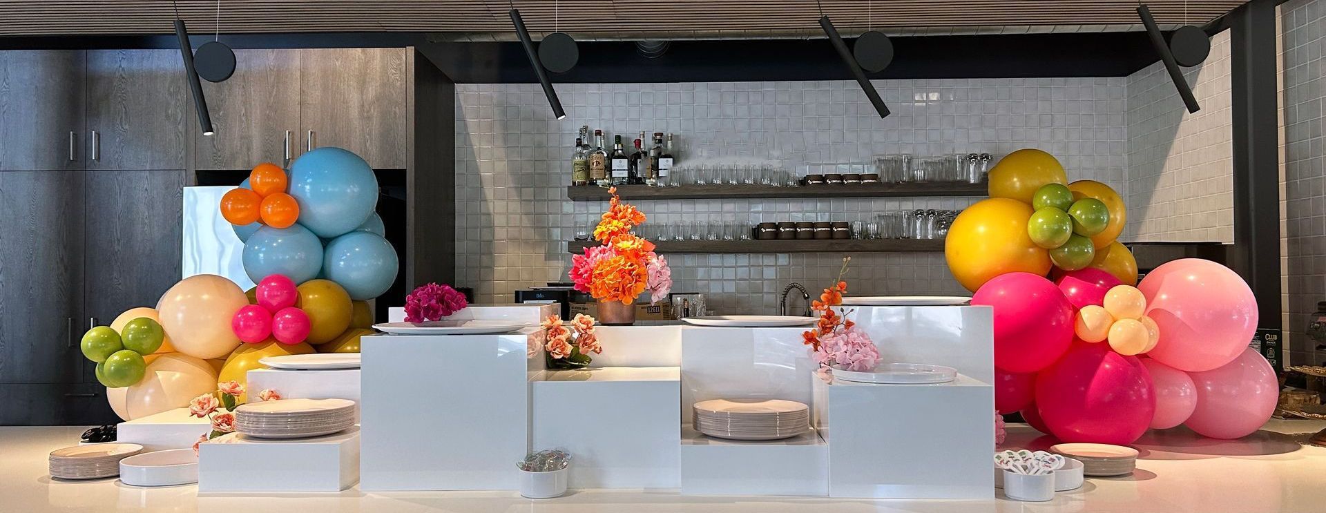 Bar decorated with colorful balloons and floral arrangements.