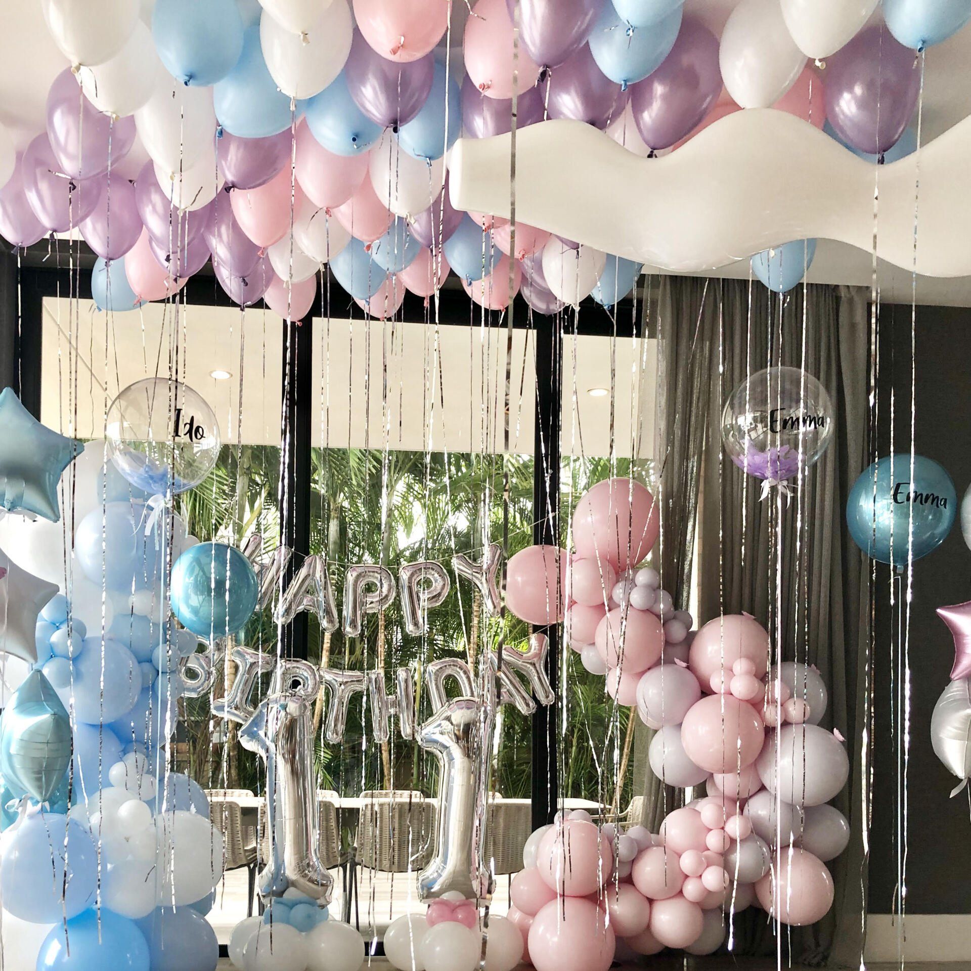 Room decorated with pastel balloons, silver streamers, and 