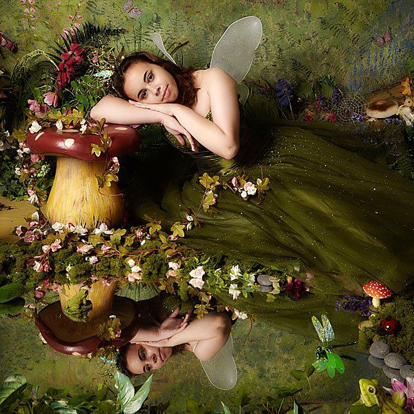 A woman in a green dress is laying on a mushroom