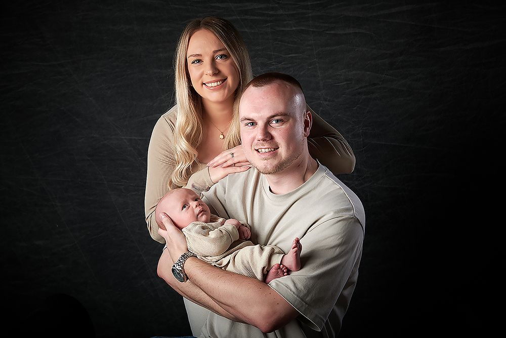 Young couple cradling their newborn baby during a portrait session at Oakley Studios, Luton