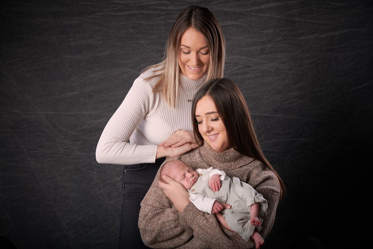 Young mum cradling her newborn baby during a family portrait session at Oakley Studios, Luton