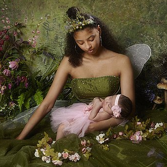 A woman dressed as a fairy is holding a baby in her arms.