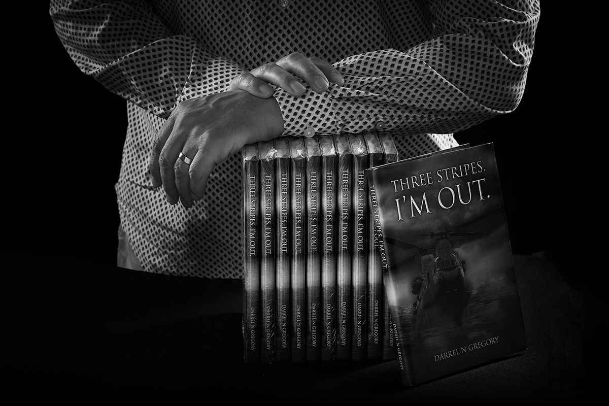 Black and white photo of Darrell Gregory holding copies of his book Three Stripes I'm Out — Oakley Studios, Luton