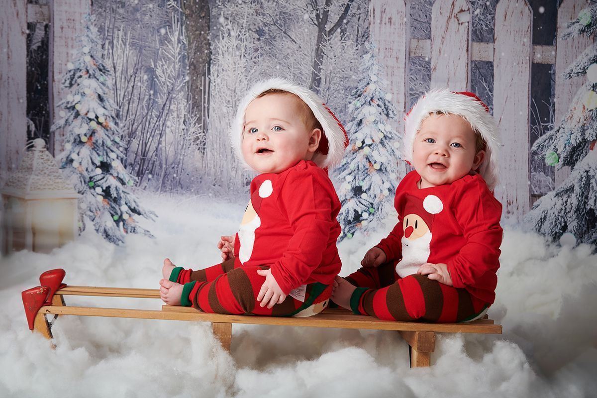 Twin children in a Christmas snow scene during a festive photoshoot at Oakley Studios, Bedfordshire