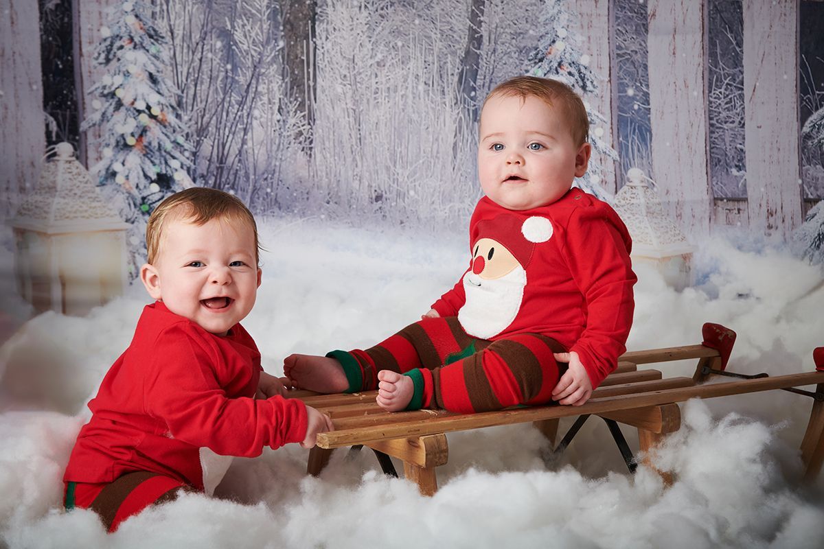 Twin children in a Christmas snow scene during a festive photoshoot at Oakley Studios, Bedfordshire