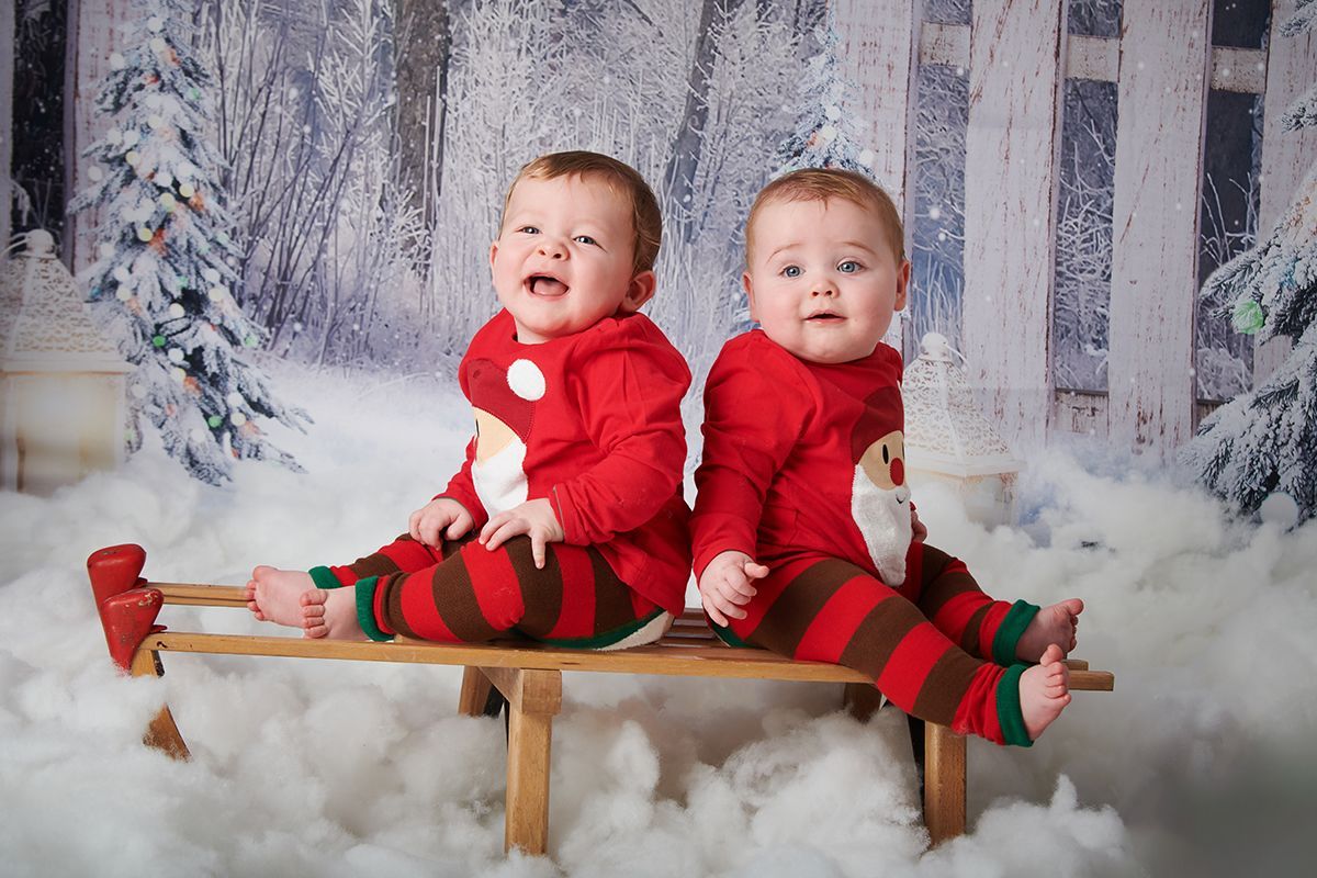 Twin children in a Christmas snow scene during a festive photoshoot at Oakley Studios, Bedfordshire