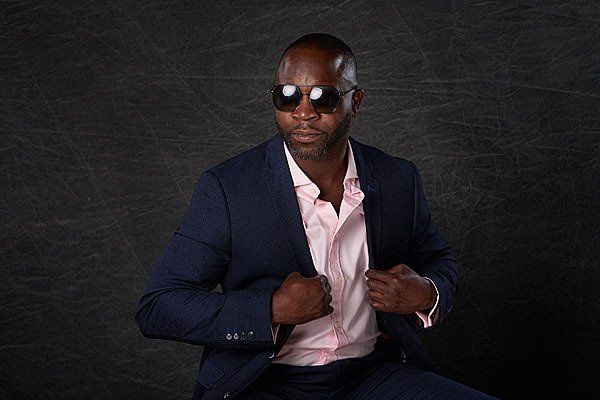 A man in a suit and sunglasses is sitting down.