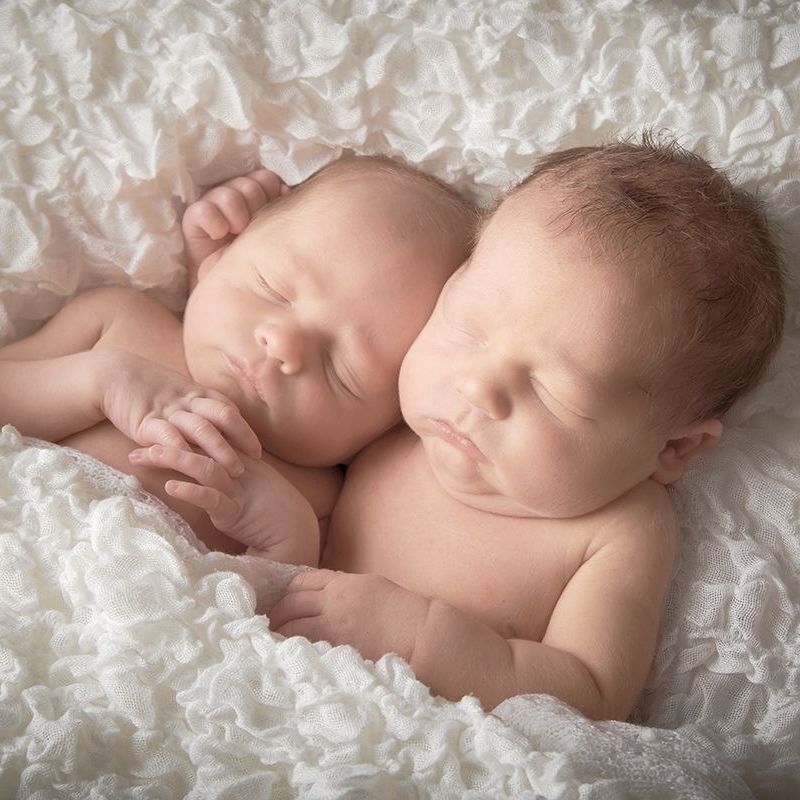 Newborn twins sleeping peacefully during a certified newborn portrait session at Oakley Studios, Luton