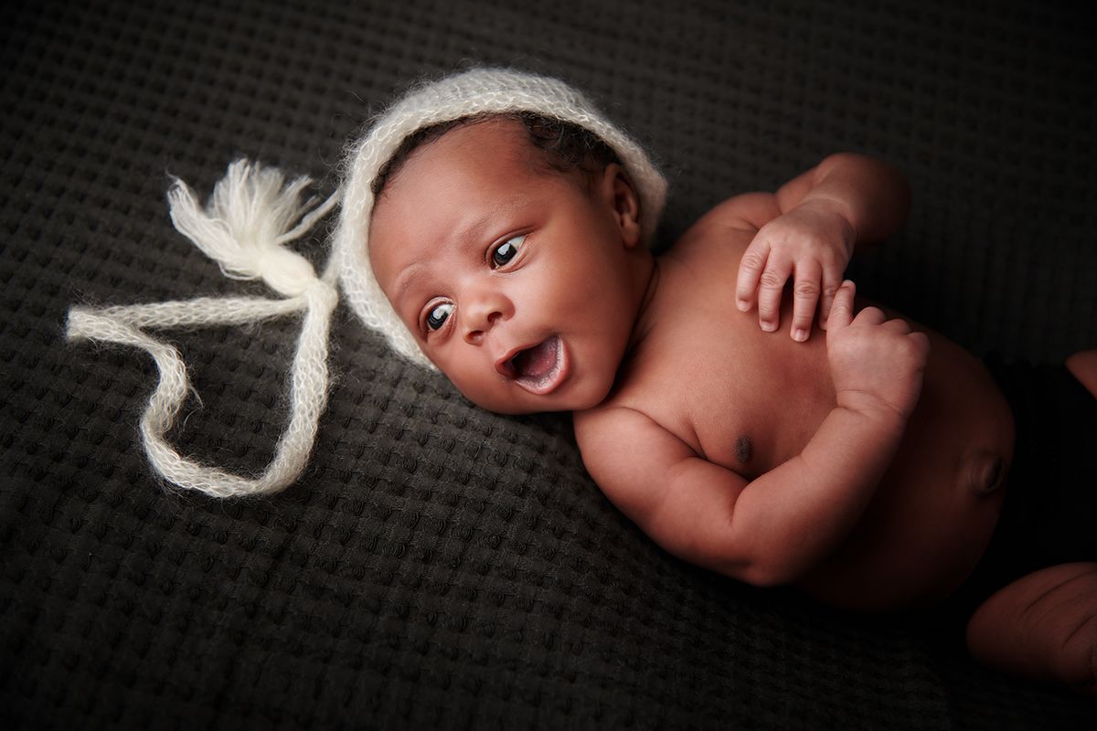 Alert newborn baby on cream background during a safe portrait session at Oakley Studios, Luton