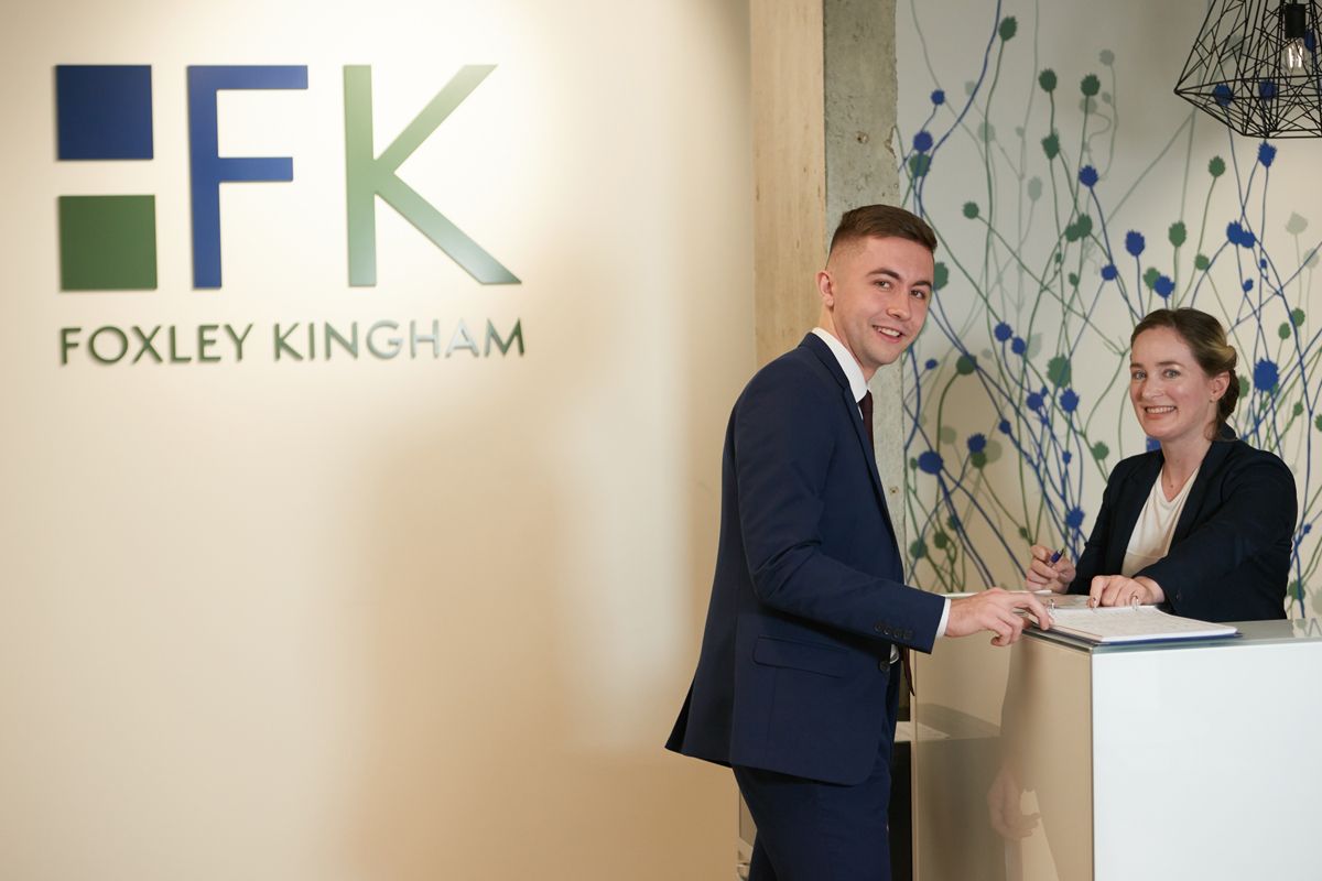 Foxley Kingham staff in front of the company sign — corporate portrait photography by Oakley Studios, Luton