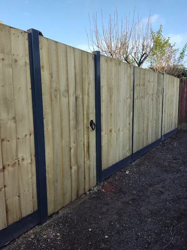 Wooden fence with dark gray trim, gate with black handle, outdoor setting.