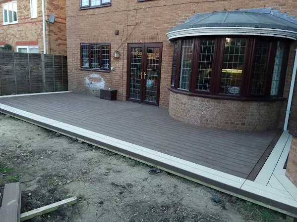 Composite deck extending from brick house with bay window.