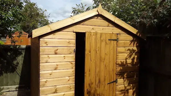 Wooden shed in a sunny garden, door ajar.