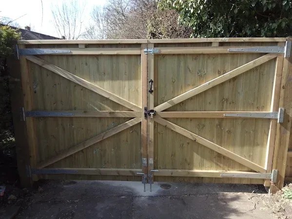 Wooden double gate with diagonal braces, silver metal hardware, and black handle.