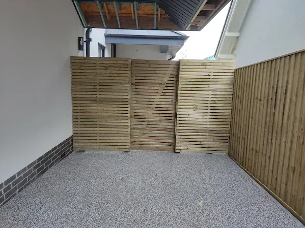 A gravel-floored outdoor space enclosed by wooden privacy screens.