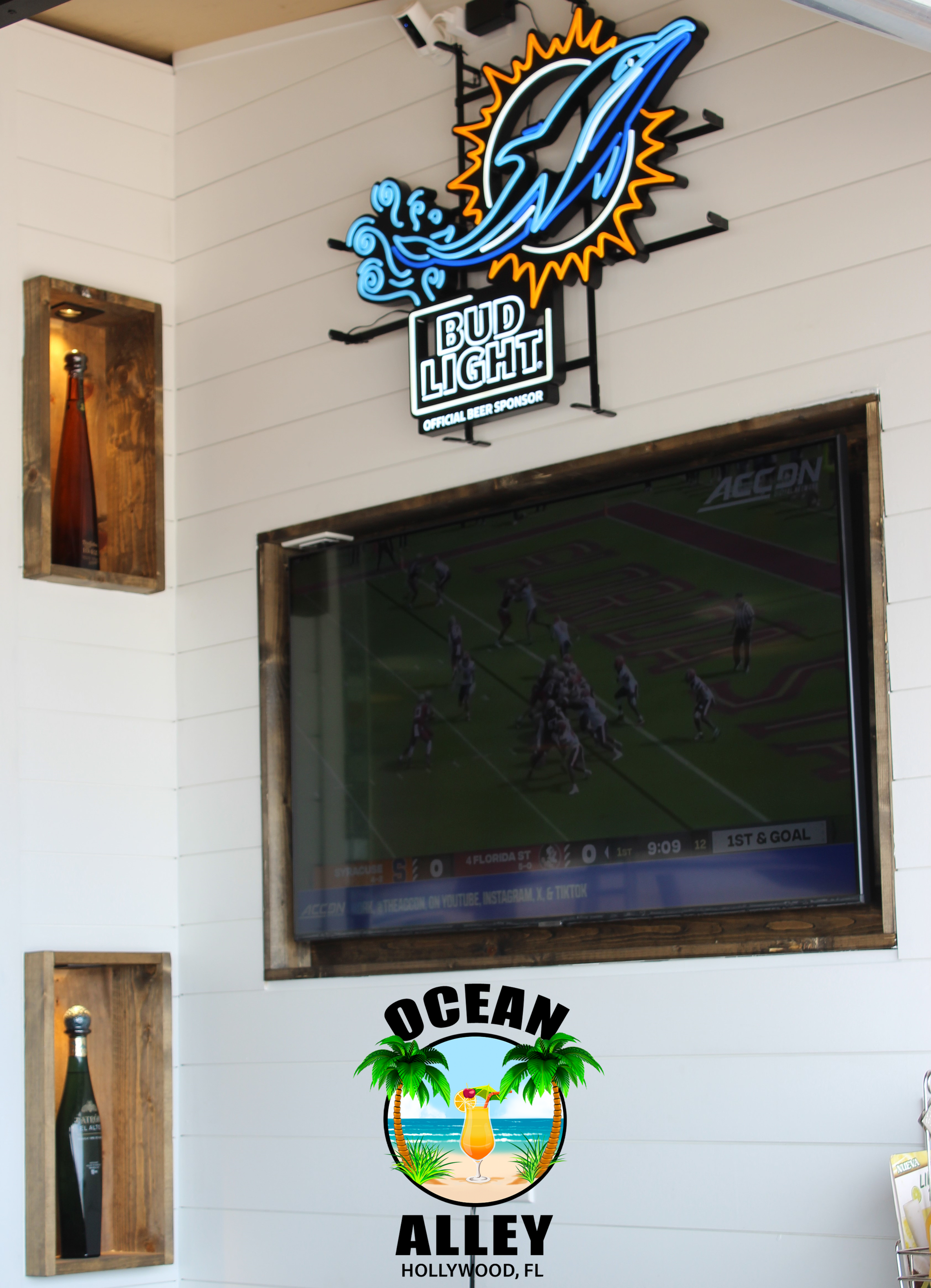 A tv mounted on a wall with a bud light sign above it