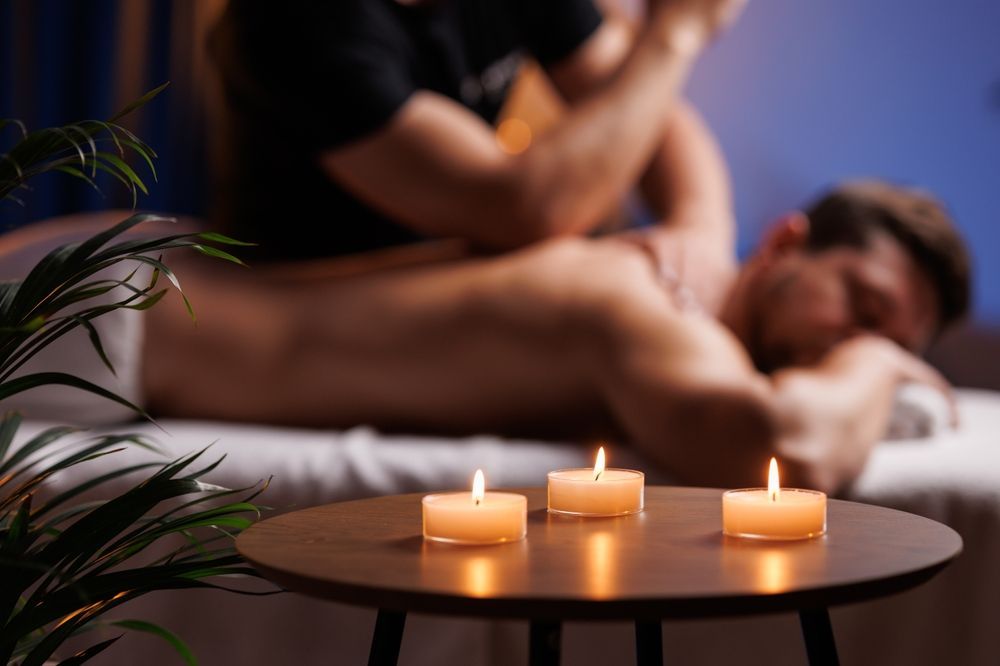Candles on a table with a blurred person receiving a massage in the background