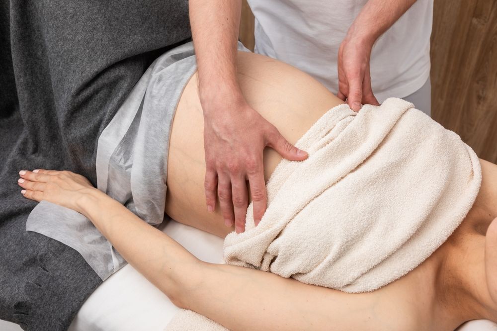 Massage therapist working on a client’s back with a white towel on a massage table