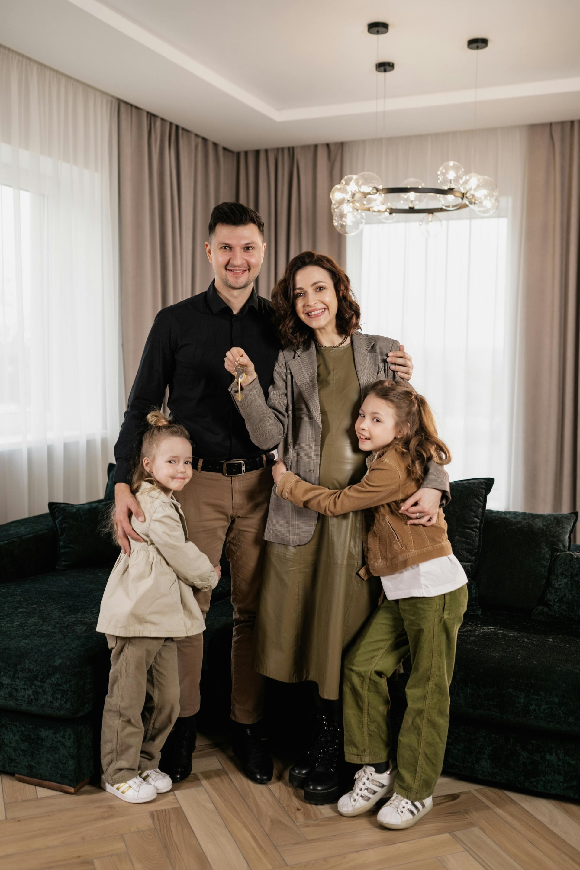 Family of four posing indoors in a bright living room, wearing coordinated neutral and brown outfits.