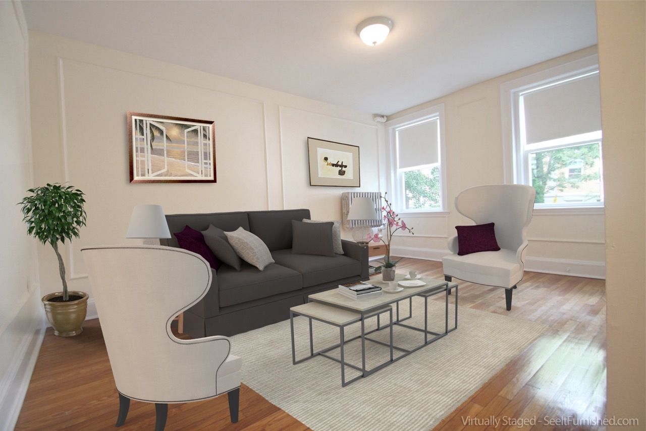Living room with gray sofa, white chairs, and metal coffee tables by large windows.