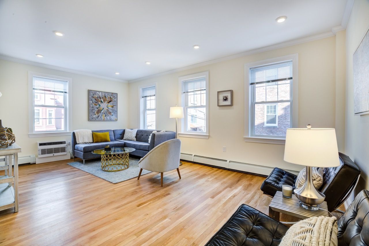 Bright living room with a sectional sofa, accent chairs, coffee table, and large windows.