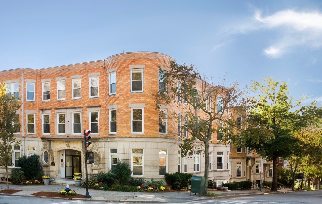 Exterior view of a brick apartment building on a tree-lined street.